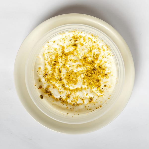 Overhead view of a creamy white dessert topped with yellow sprinkles, served in a clear bowl on a plate.