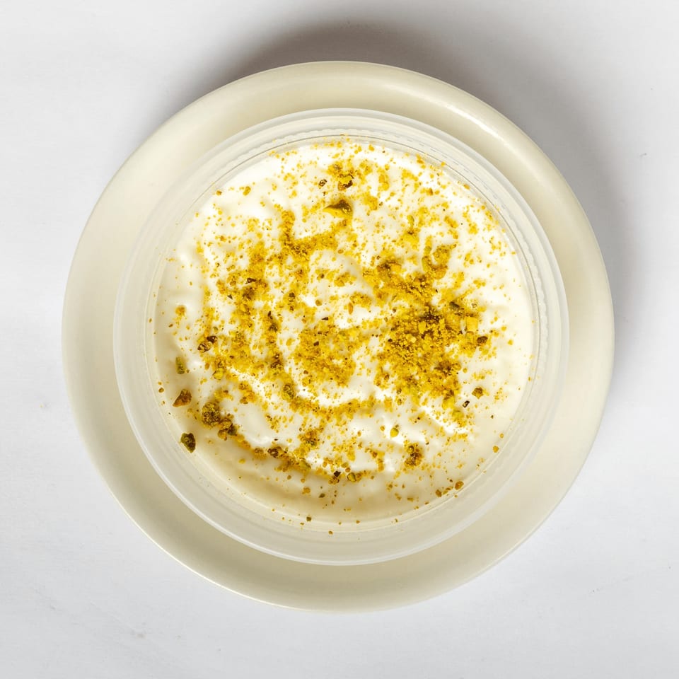 Overhead view of a creamy white dessert topped with yellow sprinkles, served in a clear bowl on a plate.