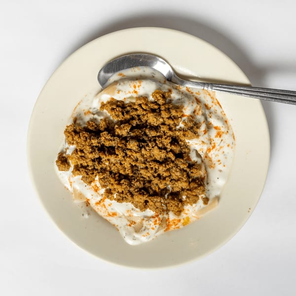Overhead view of a plate with ground meat, white sauce, and a spoon.